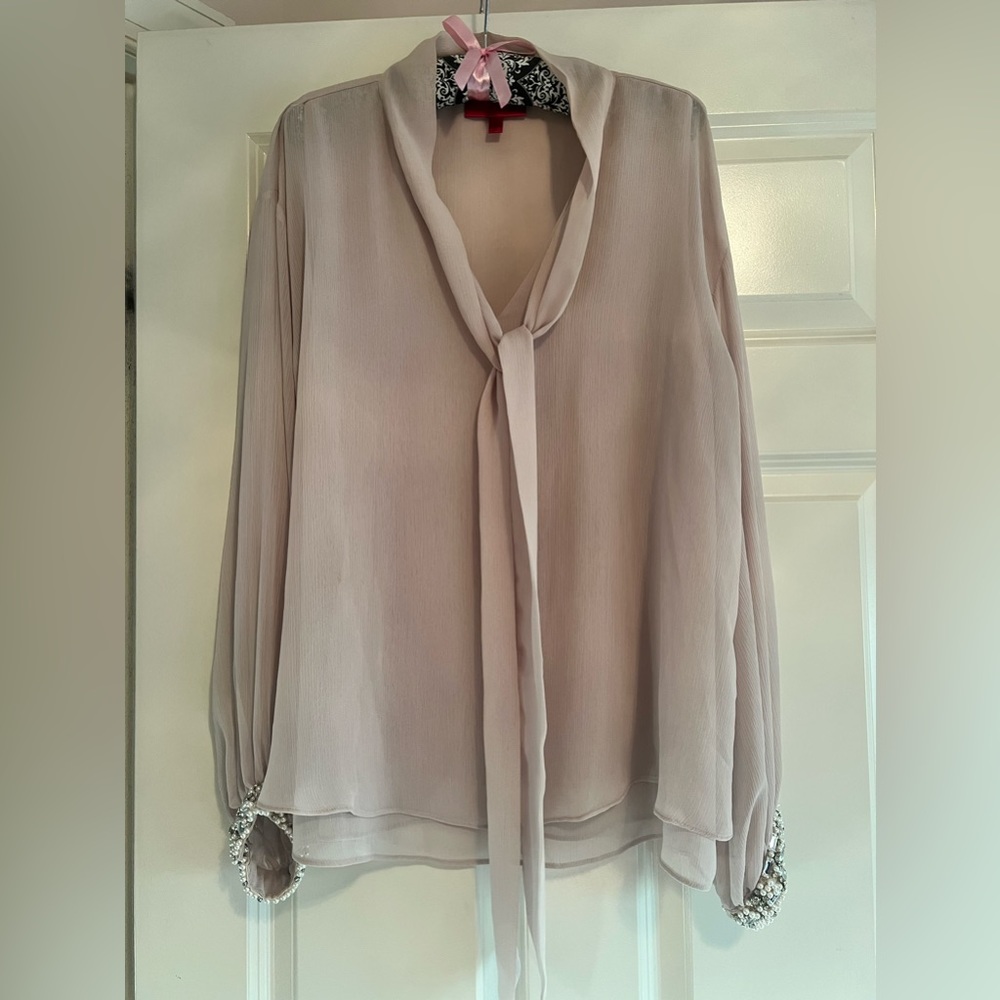 Light pink blouse with jewels and pearls at wrist.